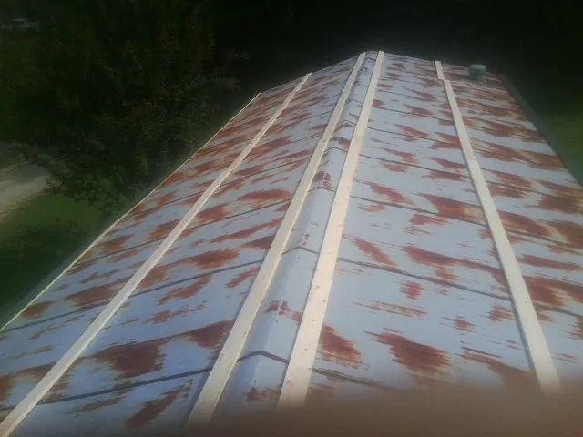 Rusted metal roof panels with new wood purlins before replacement — Storm Damage Roof Repair in Baker by Roofing Brothers