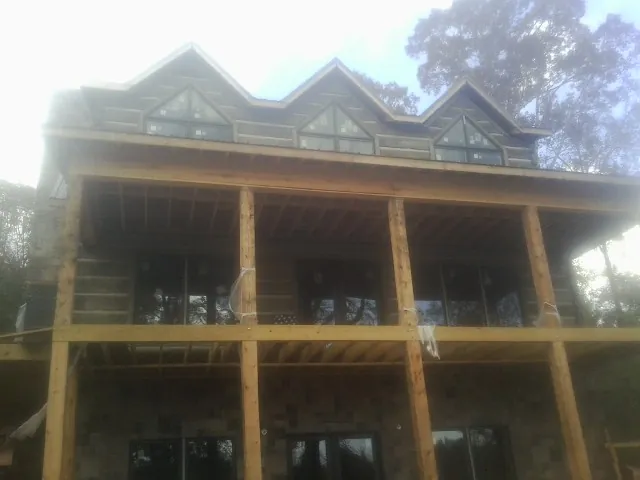Dormers and porch framing on a large log home under construction — Roof Coating work by our crew in Baker