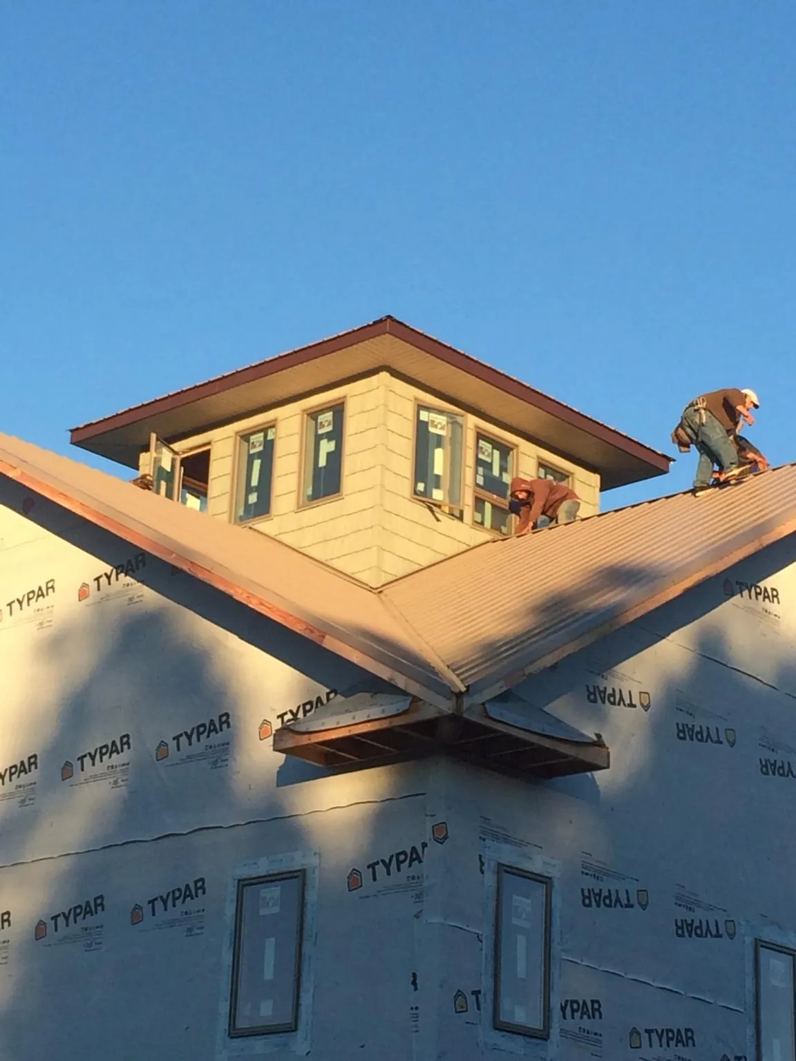 Roofers working around a rooftop cupola on a new metal roof at sunset — Roof Waterproofing in Baker by Roofing Brothers